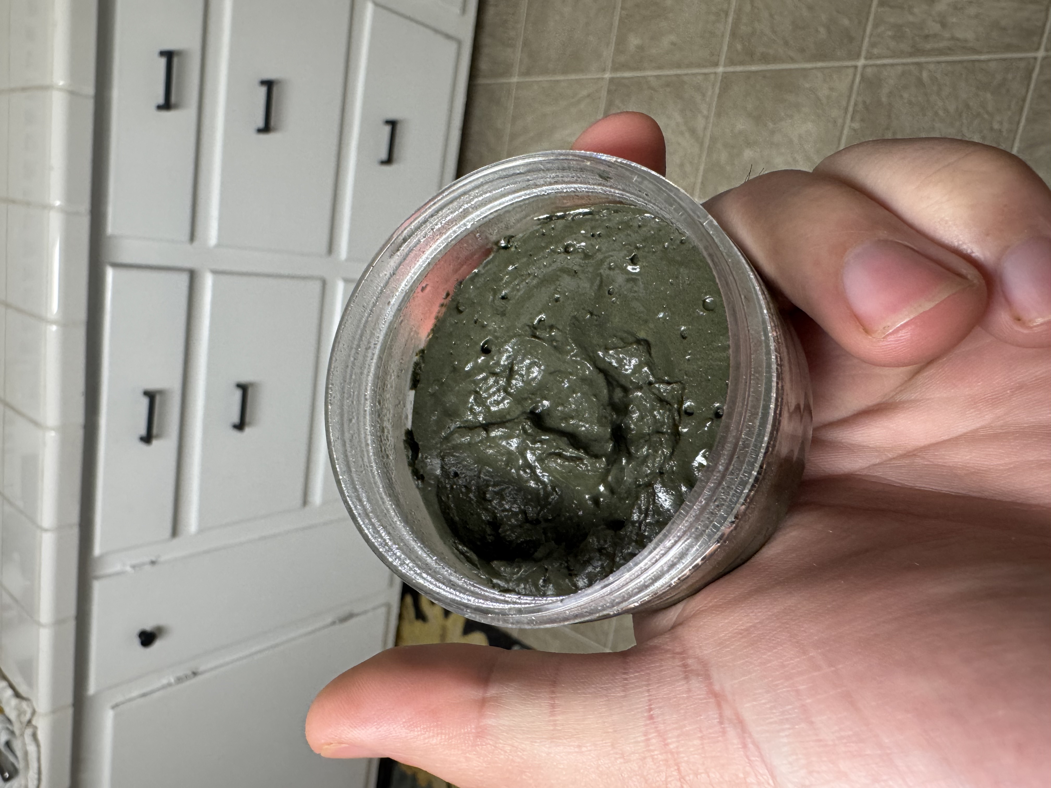 Open jar of Gator Mud showing deep dark green clay texture
